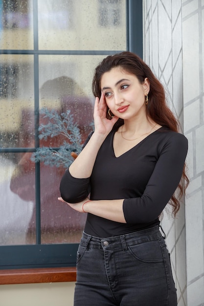 A vertical portrait of a young lady put her hand to her face and looks away High quality photo