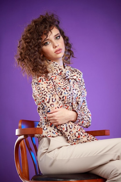 Vertical portrait of young lady sitting on a chair and looking at the camera High quality photo