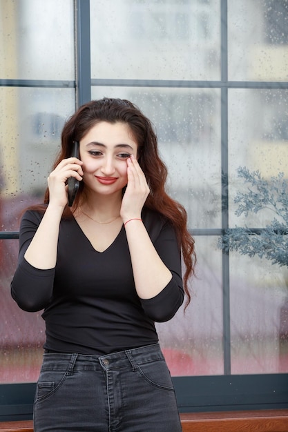 Vertical portrait of a young lady talking on the phone and crying High quality photo