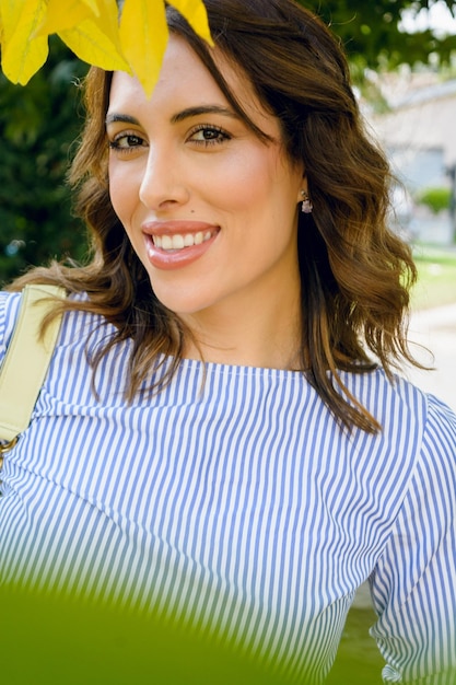 Vertical portrait of young latin woman smiling and looking at the camera outdoors