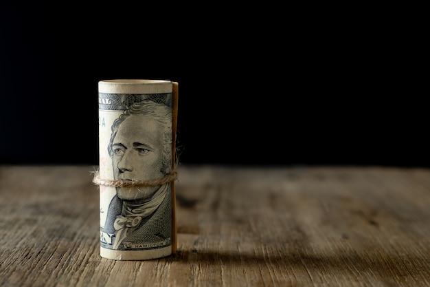 Vertical roll of American dollars banknotes on old wooden table