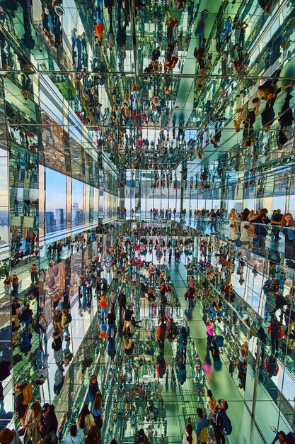 Vertical room of hundreds of tourists reflecting in mirrors everywhere in skyscraper overlooking New