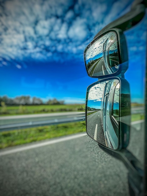 Vertical selective focus shot of the reflection of asphalt highway in side mirror of a truck