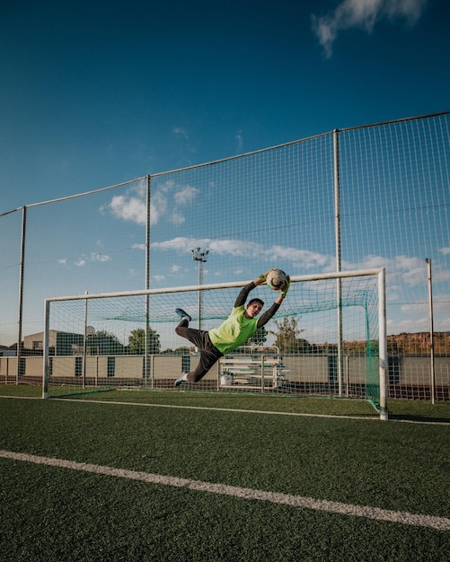 Foto tiro verticale di un portiere che cerca di fermare un tiro.