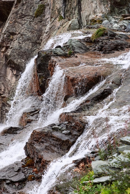 Vertical shot of alpine waterfall with contrasting textures and colors of granite rocks