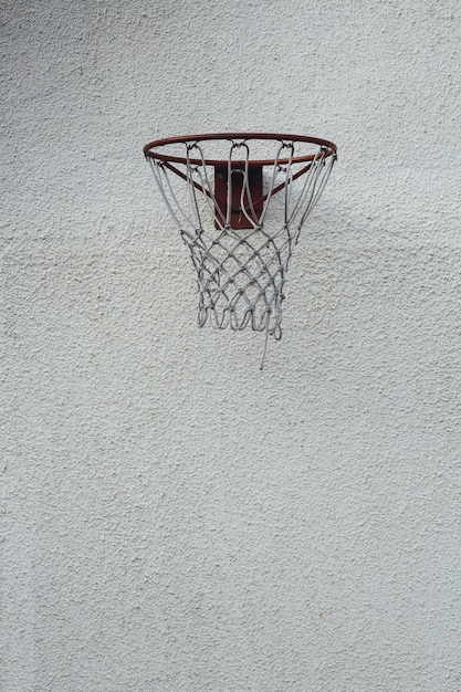 A vertical shot of a basketball hoop on a white concrete wall