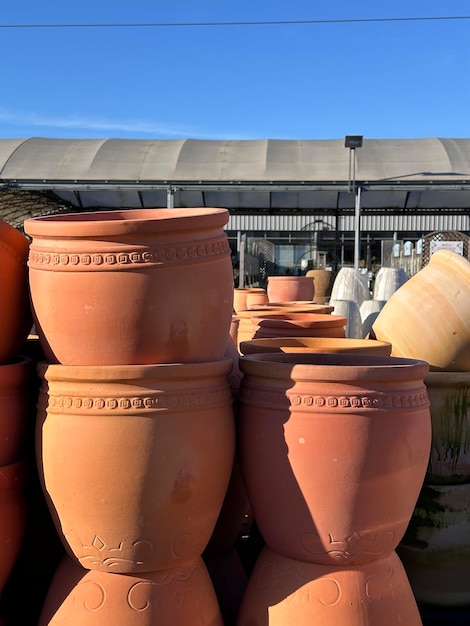 Photo vertical shot of big plant pots stacked in garden center outdoors in the sun
