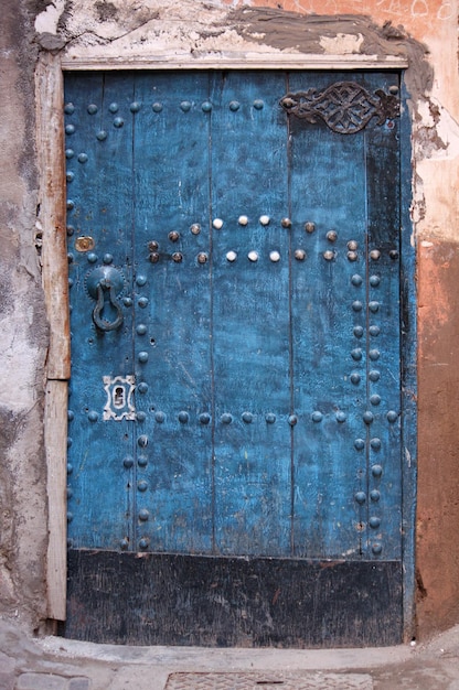 Vertical shot of a blue door with circular bolts sticking out of it