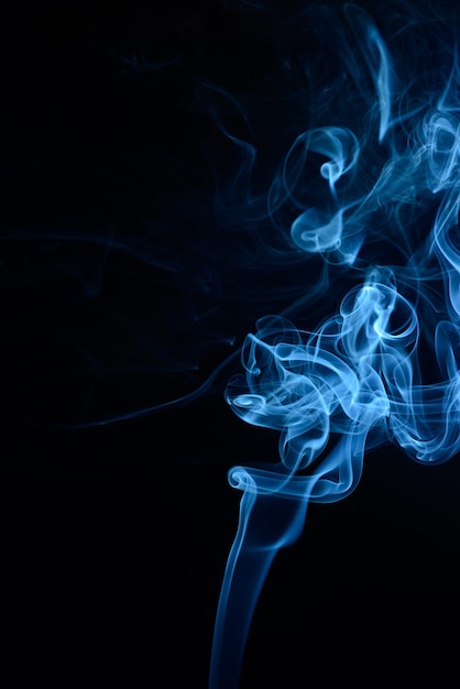 Вертикальный снимок синего табачного дыма на черном фоне