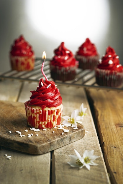 Vertical shot of a candle cupcake with red cream