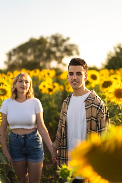 Vertical shot of a Caucasian lovely couple at the sunflowers field in Spain