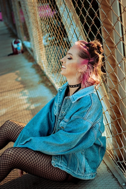 Vertical shot of a cheerful young Caucasian lady with pink hair gothic style makeup and clothing