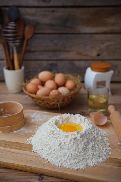 Vertical shot of a chicken egg and wheat flour on a wooden table