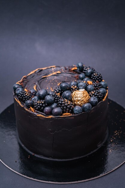 Vertical shot of a chocolate cake with blueberries and blackberries