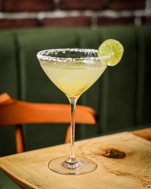 Vertical shot of a cocktail margarita on a wooden table in the restaurant