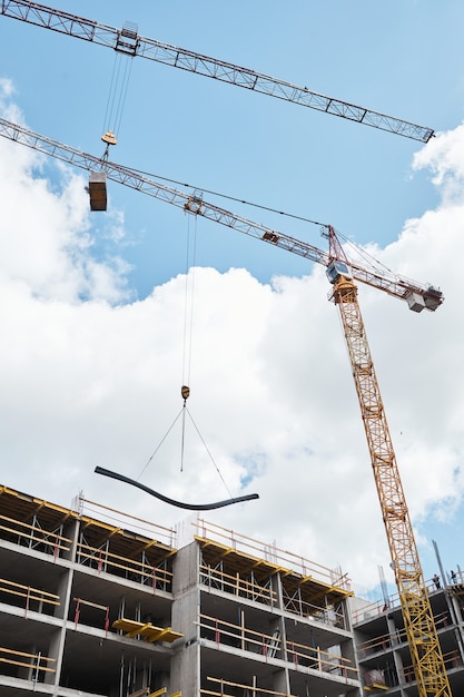 Colpo verticale della gru da costruzione che costruisce una casa residenziale contro il cielo blu, copia spazio