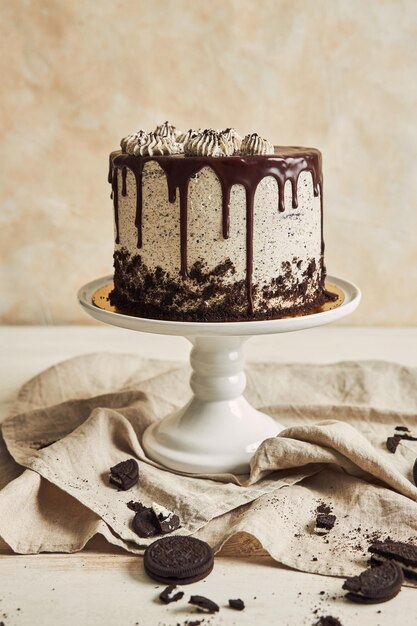 Photo vertical shot of a delicious chocolate cake with cookies on a tray on the table