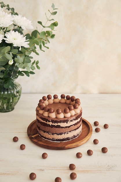 Вертикальный снимок вкусного шоколадного торта с шоколадными шариками и кремом на белом столе