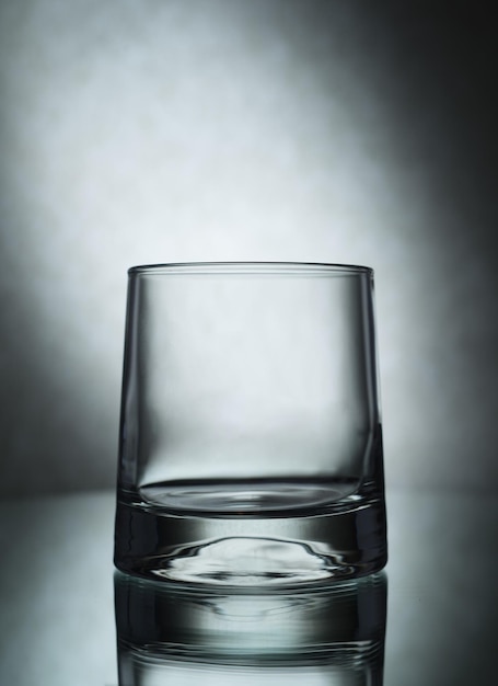 Вертикальный снимок пустого стакана на сером фоне