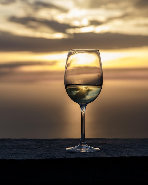 Ripresa verticale di un bicchiere di vino sullo sfondo di un bel tramonto