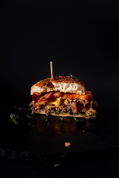 Vertical shot of half of a burger on a black background