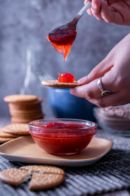 Vertical shot of hands making fresh Maria cookie (galletas Maria) with strawberry jam