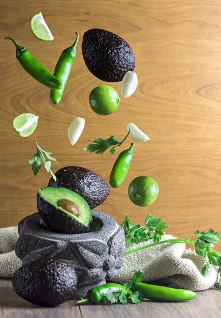 Vertical shot of healthy vegetables and fruits flying into the stone bowl put on a kitchen table