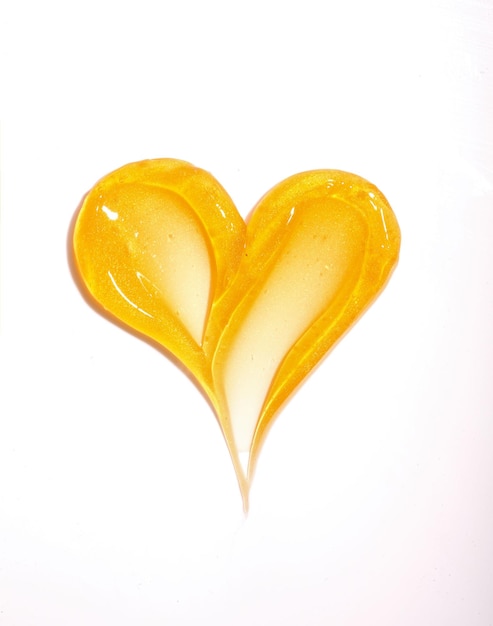 Вертикальный снимок золотых текстур для ухода за кожей в форме сердца на белом фоне