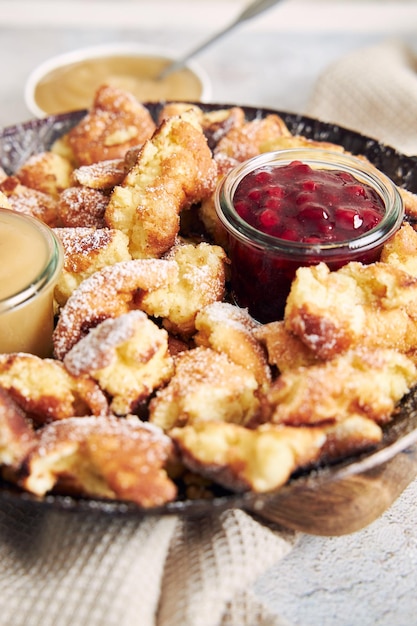 Vertical shot of kaiserschmarrn with torn pancakes, cranberries jam, and apple puree on a table