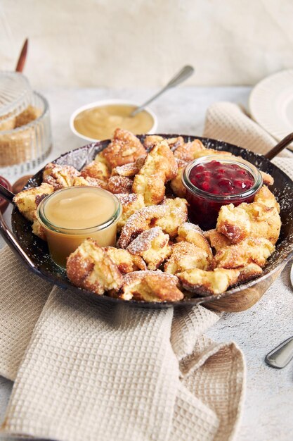 テーブルの上に引き裂かれたパンケーキ、クランベリー ジャム、リンゴのピューレを添えた kaiserschmarrn の垂直ショット