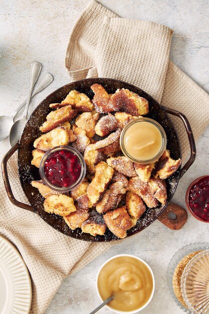 Vertical shot of kaiserschmarrn with torn pancakes, cranberries jam, and apple puree on a table