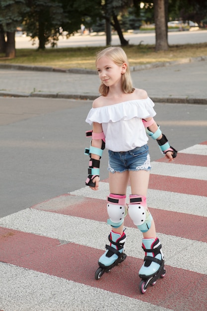 Vertical shot of a lovely young girl wearing protective gear while rollerblading