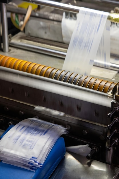 Вертикальный снимок машины, печатающей этикетки для шприцев на складе медицинского производства.