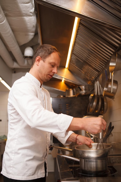 Vertical shot of a male chef whisking sauce in a bowl