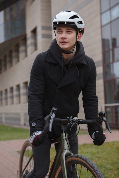 Vertical shot of a man riding bicycle int he city, wearing helmet