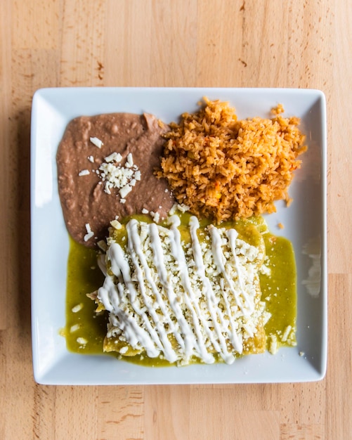 Vertical shot of a Mexican dish of enchiladas verdes with rice and beans