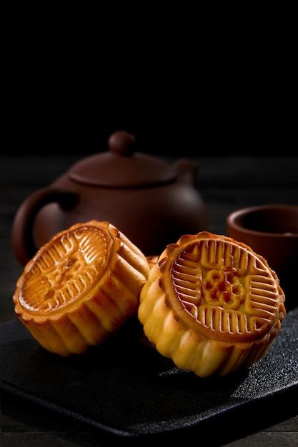 vertical shot of mooncakes with a cup of tea on a black surface