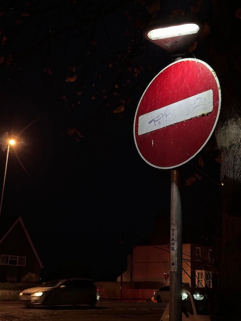 Foto ritratto verticale di un segnale stradale di proibizione di ingresso illuminato di notte