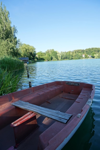 Фото Вертикальный снимок лодки на воде с голубым небом на заднем плане