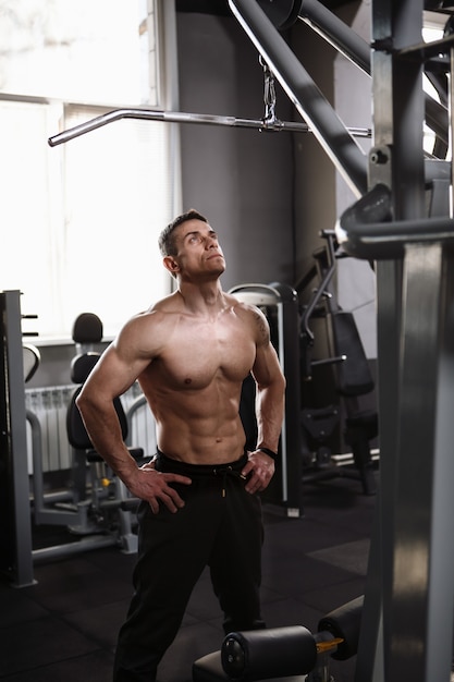 Фото Вертикальный снимок спортсмена без рубашки с разорванным телом, стоящего в тренажерном зале