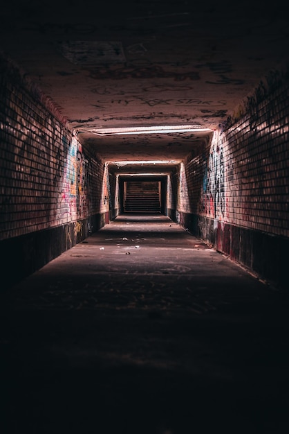 Vertical shot of an old empty underground corridor tunnel of an urban city with graffiti walls