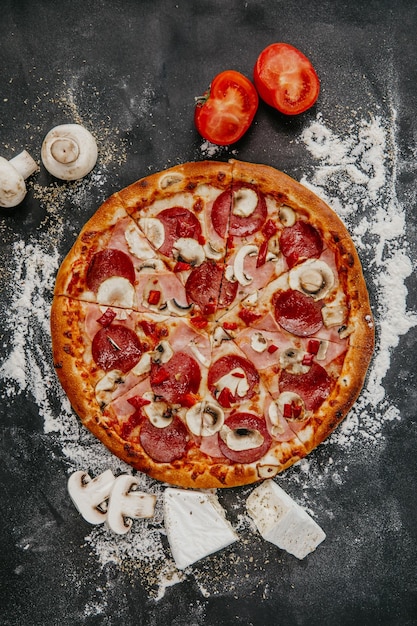 Vertical shot of a pepperoni and mushroom pizza on a black background