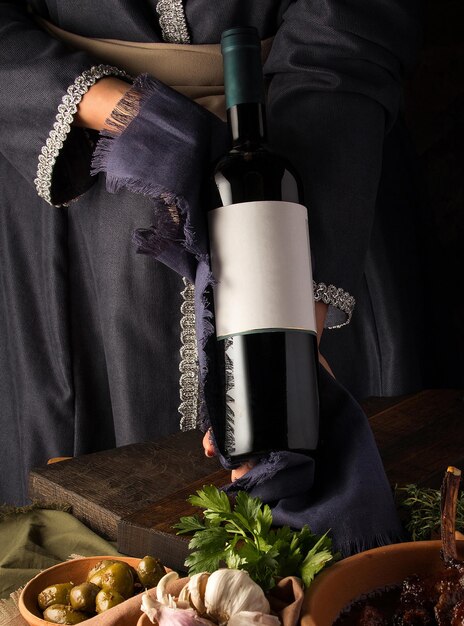 Vertical shot of a person in a traditional costume showing a wine bottle