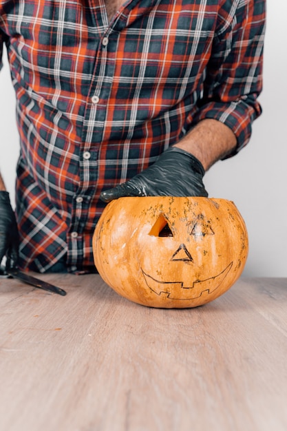 Photo a vertical shot of a person wearing gloves and carving a pumpkin for halloween