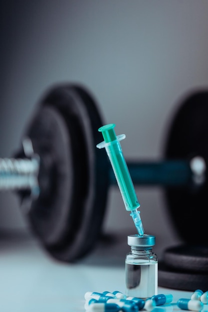 Вертикальный снимок фармацевтического шприца с иглой в лекарствах и таблетках - незаконные допинговые препараты