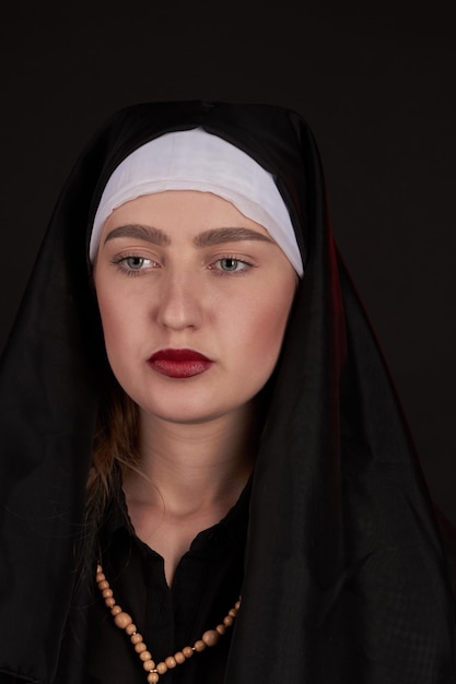 Vertical shot portrait of young nun on black background look with no emotions