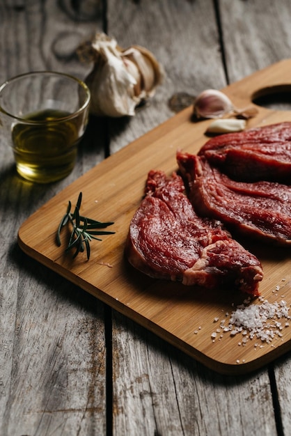 Vertical shot of raw meats on a wooden board