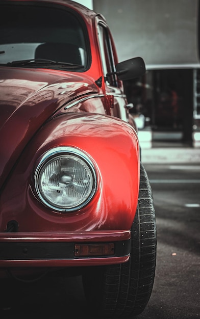 A vertical shot of a red vintage car parked outdoors at daytime