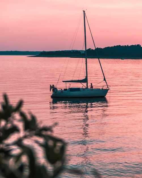 Vertical shot of a sailing boat in the sea during sunset