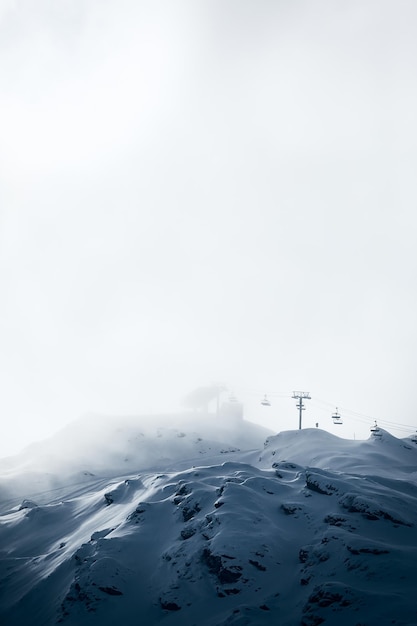 Vertical shot of ski way in high snowcapped mountains with ropeway on the background